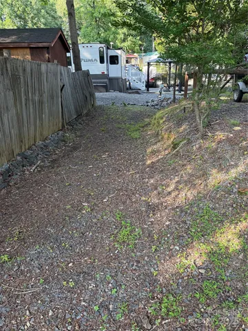 a view of a backyard with large trees and wooden fence