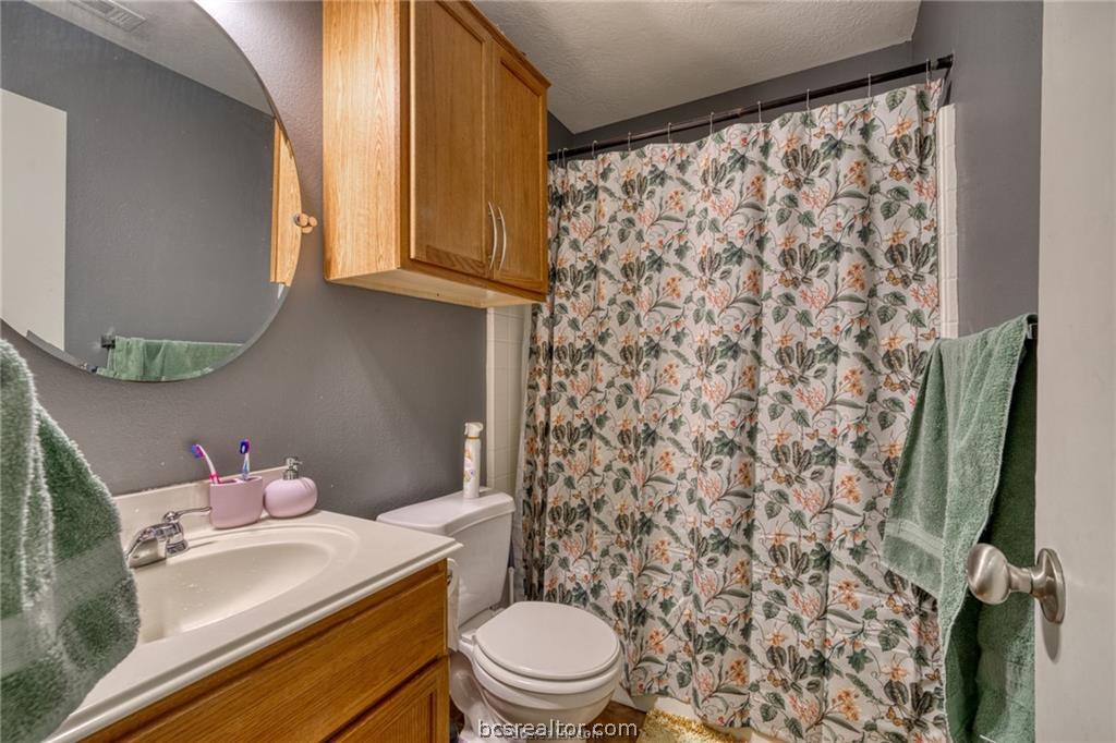 1015 Fallbrook Loop College Station, TX 77845 - Photo 11 of 15 Full bathroom with toilet, a textured ceiling, vanity, and a shower with curtain