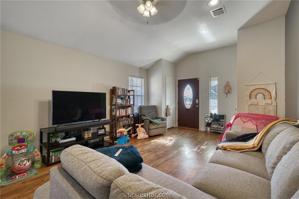 1015 Fallbrook Loop College Station, TX 77845 - Photo 3 of 15 Living room with lofted ceiling, ceiling fan, wood finished floors, and visible vents