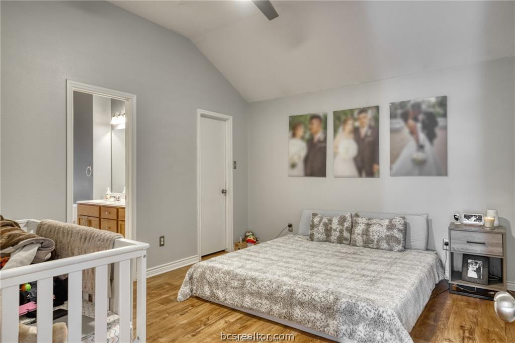 1015 Fallbrook Loop College Station, TX 77845 - Photo 7 of 15 Bedroom with baseboards, a ceiling fan, connected bathroom, wood finished floors, and vaulted ceiling