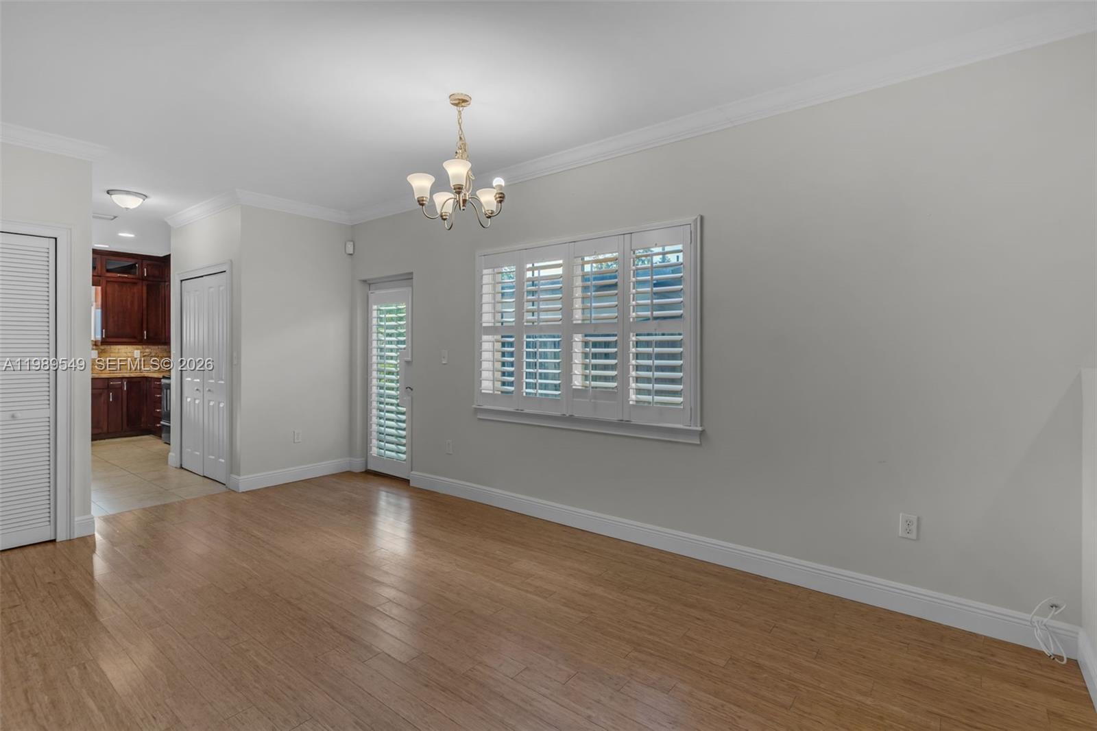 7048 Southwest 83rd Court Miami, FL 33143 - Photo 14 of 38 an empty room with wooden floor chandelier and windows