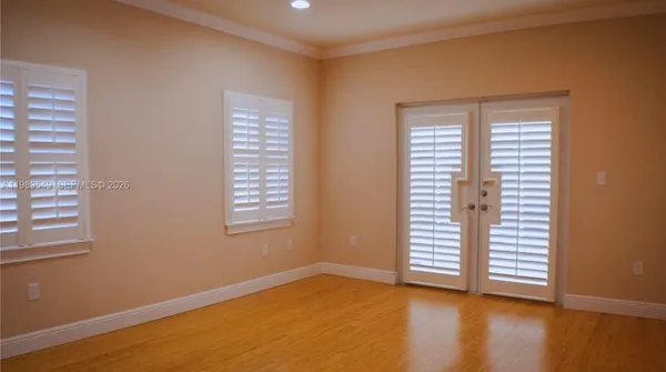 a view of an empty room with a window and hardwood floor