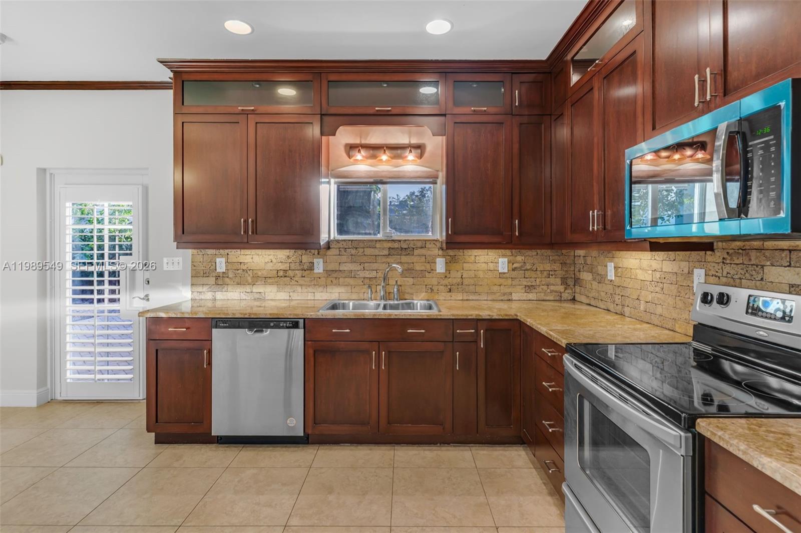 7048 Southwest 83rd Court Miami, FL 33143 - Photo 7 of 38 a kitchen with stainless steel appliances granite countertop a stove sink and cabinets