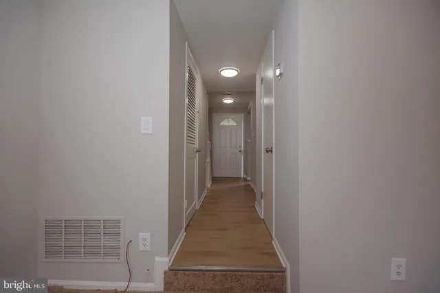 a view of a hallway with wooden floor and a bathroom