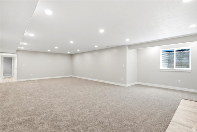 2973 West Red Sand Rd Haven Ogden, UT 84401 - Photo 20 of 30 Expansive carpeted room featuring recessed lighting, a window with a stone-look exterior, light gray walls, white baseboards, and a doorway leading to a space with wood-finish flooring