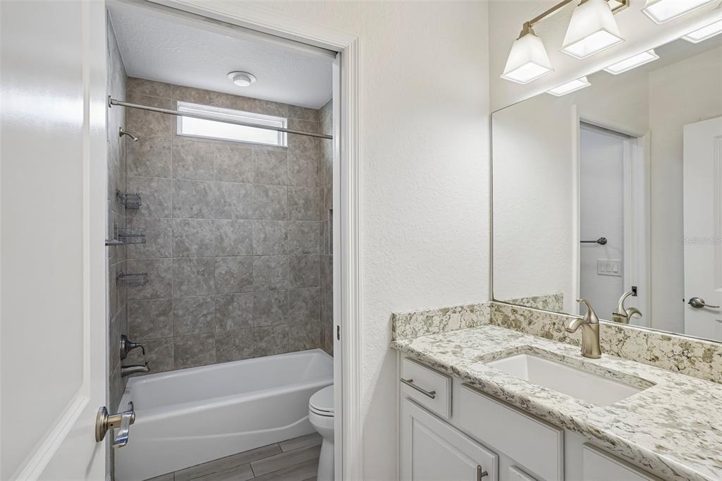 10339 Addison Shore Way Oxford, FL 34484 - Photo 47 of 54 a bathroom with a granite countertop sink mirror toilet and bathtub