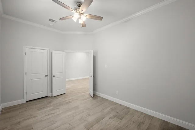 an empty room with wooden floor closet and ceiling fan