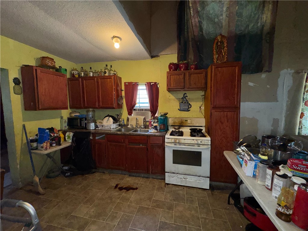 122 West 5th Street Alice, TX 78332 - Photo 13 of 40 a kitchen with a stove a refrigerator and wooden cabinets