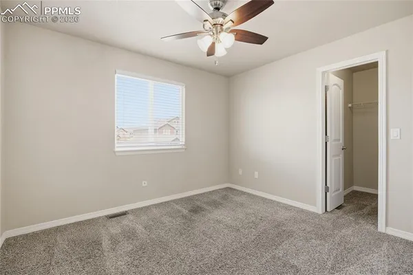 an empty room with ceiling fan and window