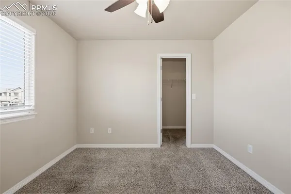 an empty room with a chandelier fan and closet