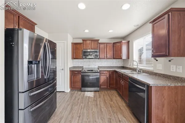 a kitchen with a refrigerator sink and wooden cabinets