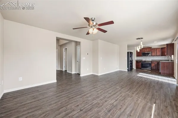 a view of a room with wooden floor and a ceiling fan