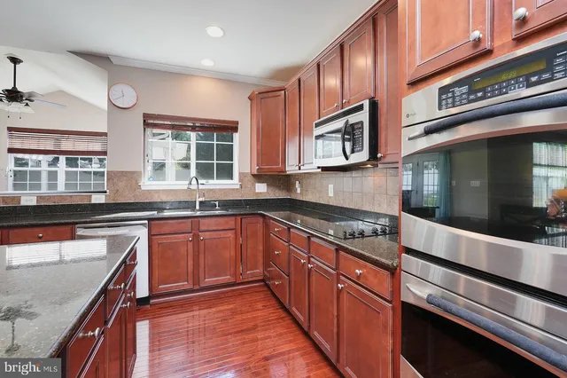 a kitchen with stainless steel appliances granite countertop wooden cabinets a sink and a stove