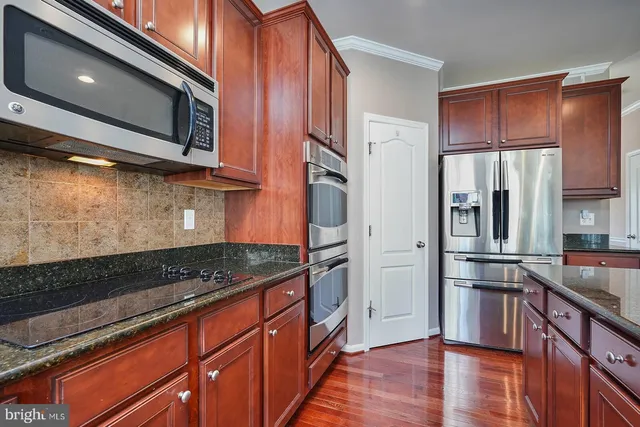 a kitchen with stainless steel appliances granite countertop a refrigerator and a stove top oven