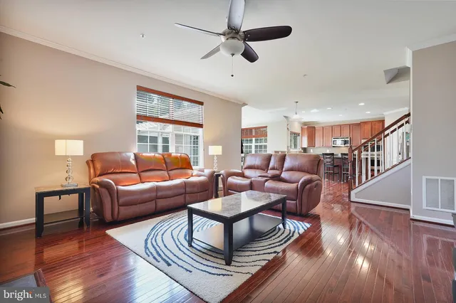 a living room with furniture a ceiling fan and a wooden floor