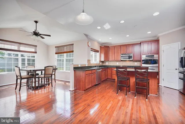 a kitchen with stainless steel appliances kitchen island granite countertop wooden floors and wooden cabinets