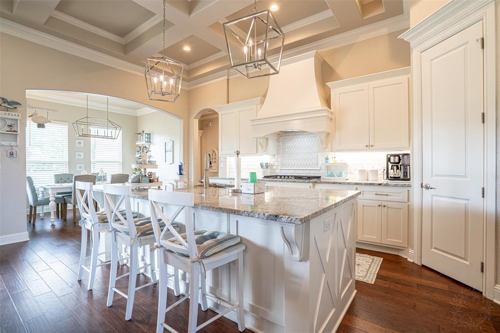 1920 Meander Road Granbury, TX 76049 - Photo 10 of 40 Kitchen featuring a large island with granite countertop, white cabinetry, wood-finish flooring, a coffered ceiling, and pendant lighting fixtures