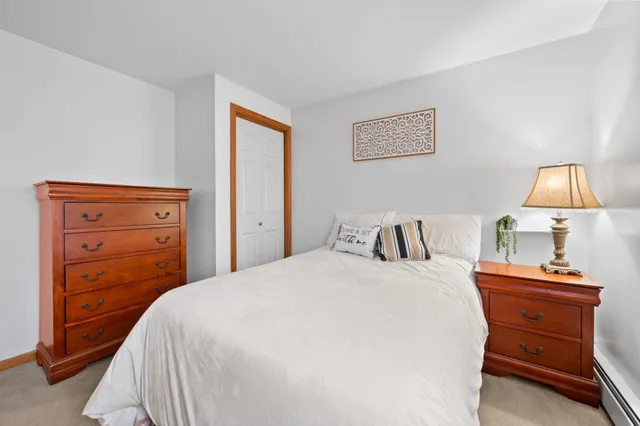 a bedroom with a bed and a lamp on dresser