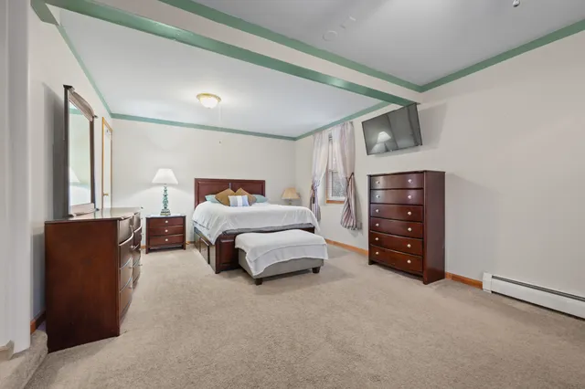 a bedroom with a bed and a large mirror on dresser next to a window
