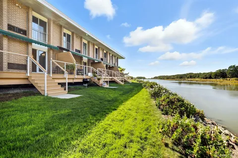 a view of a balcony with wooden chairs and floor to ceiling window next to a yard