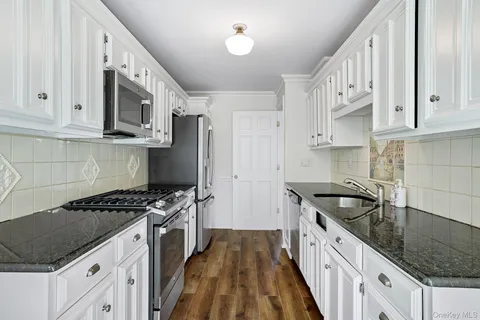 a kitchen with granite countertop a sink stove and cabinets