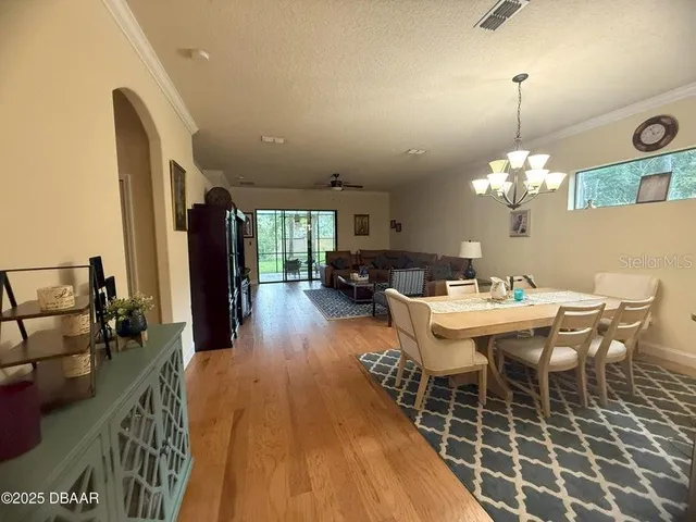 a dining room with wooden floor a chandelier a wooden table and chairs