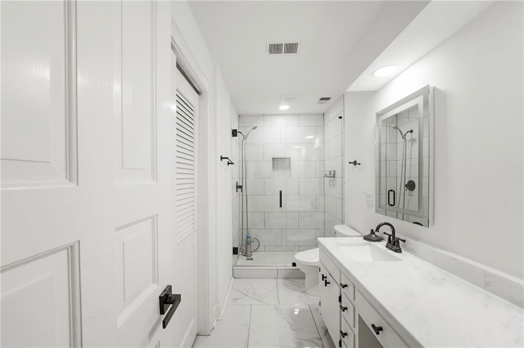 3649 Peachtree Road Northeast, Unit 305 Atlanta, GA 30319 - Photo 43 of 58 a bathroom with a double vanity sink a toilet a mirror and shower