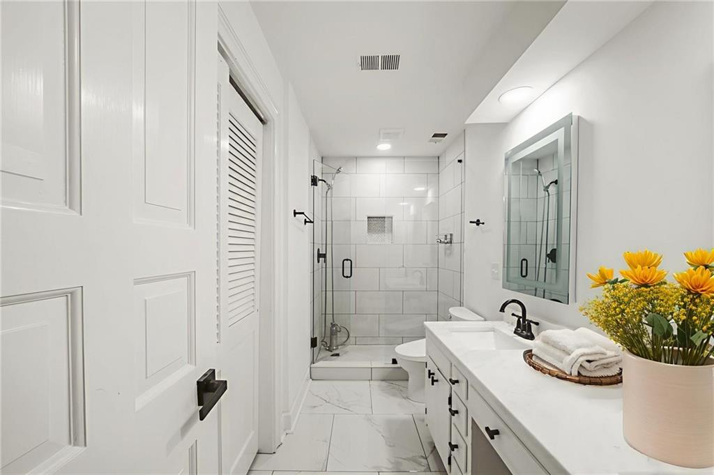 3649 Peachtree Road Northeast, Unit 305 Atlanta, GA 30319 - Photo 10 of 58 a bathroom with a double vanity sink a toilet a mirror and shower