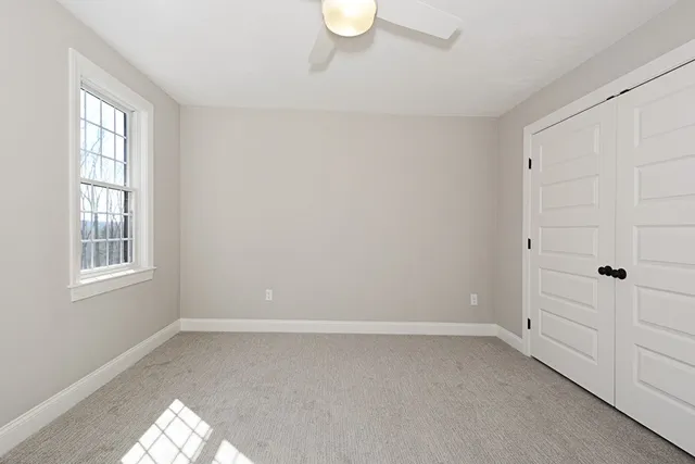 a view of an empty room with a window and closet area