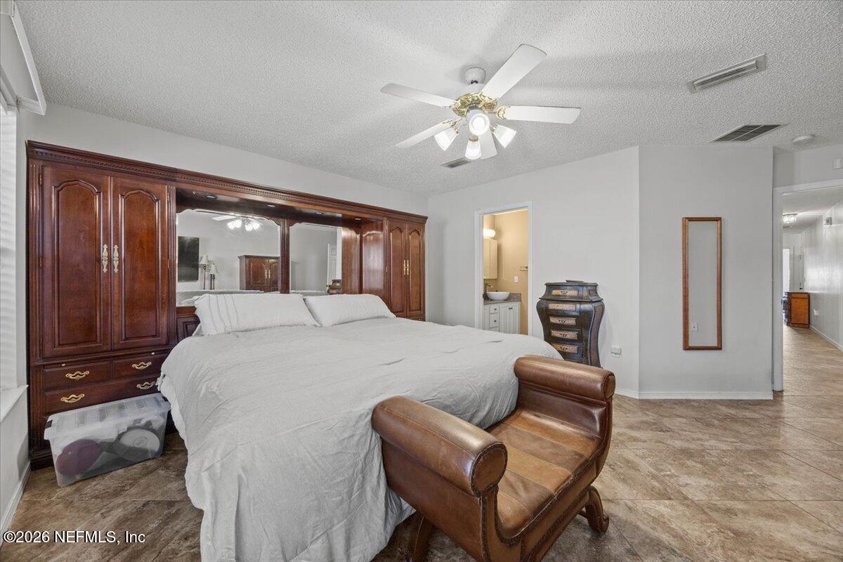 9750 Brockham Court Jacksonville, FL 32221 - Photo 25 of 39 a bedroom with a large bed a chandelier and dresser
