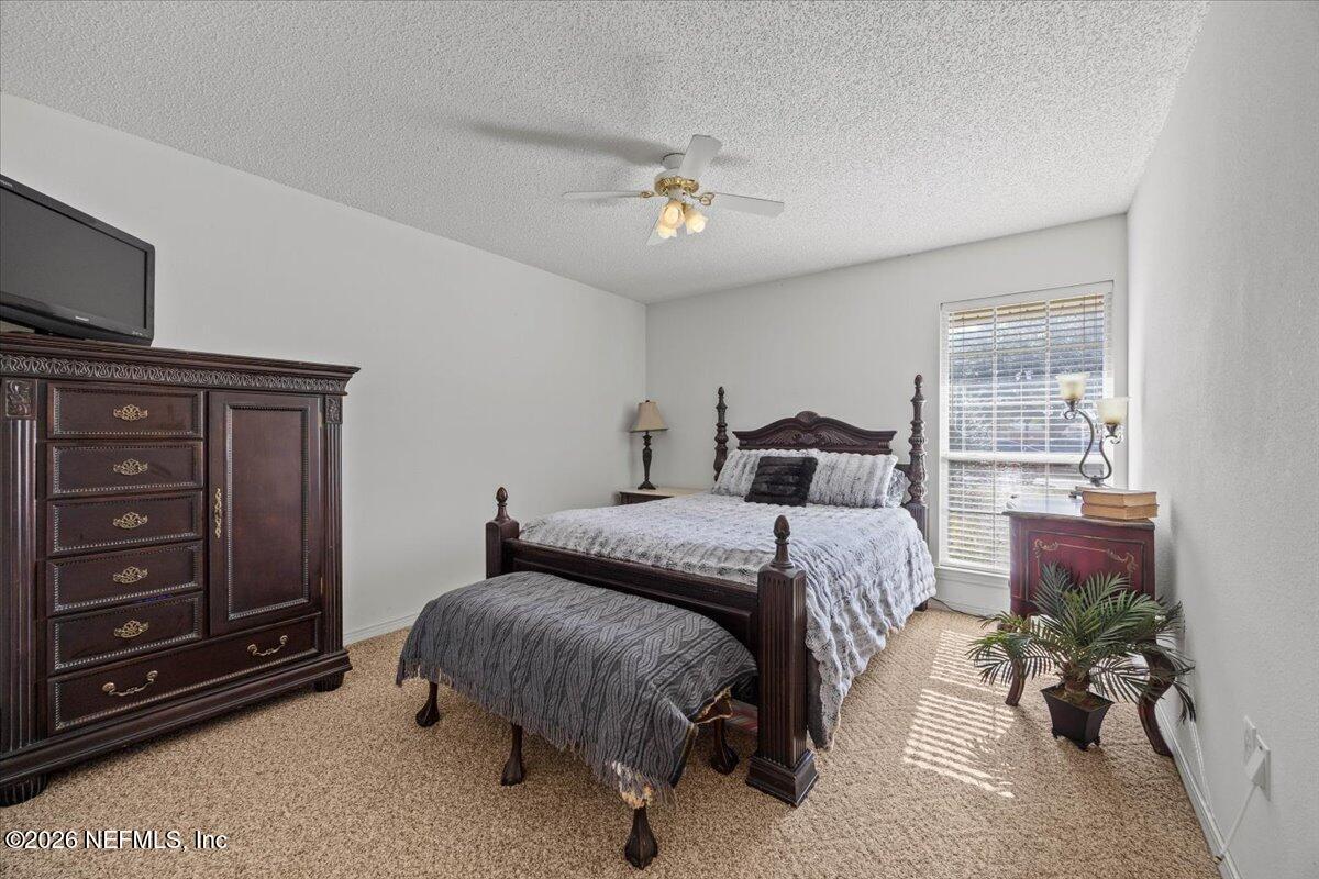 9750 Brockham Court Jacksonville, FL 32221 - Photo 32 of 39 a bedroom with a bed and a chandelier