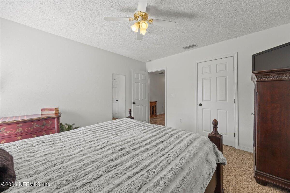 9750 Brockham Court Jacksonville, FL 32221 - Photo 33 of 39 a bedroom with a bed and a chandelier
