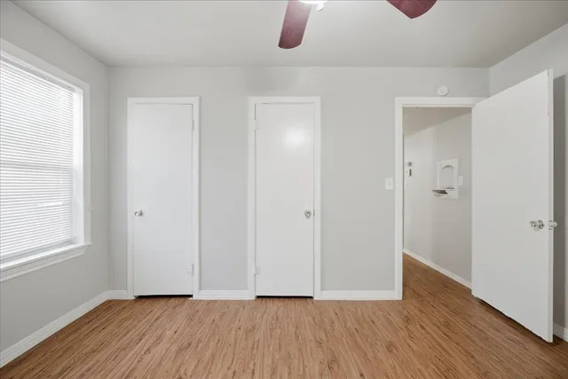 a view of an empty room with wooden floor and a window