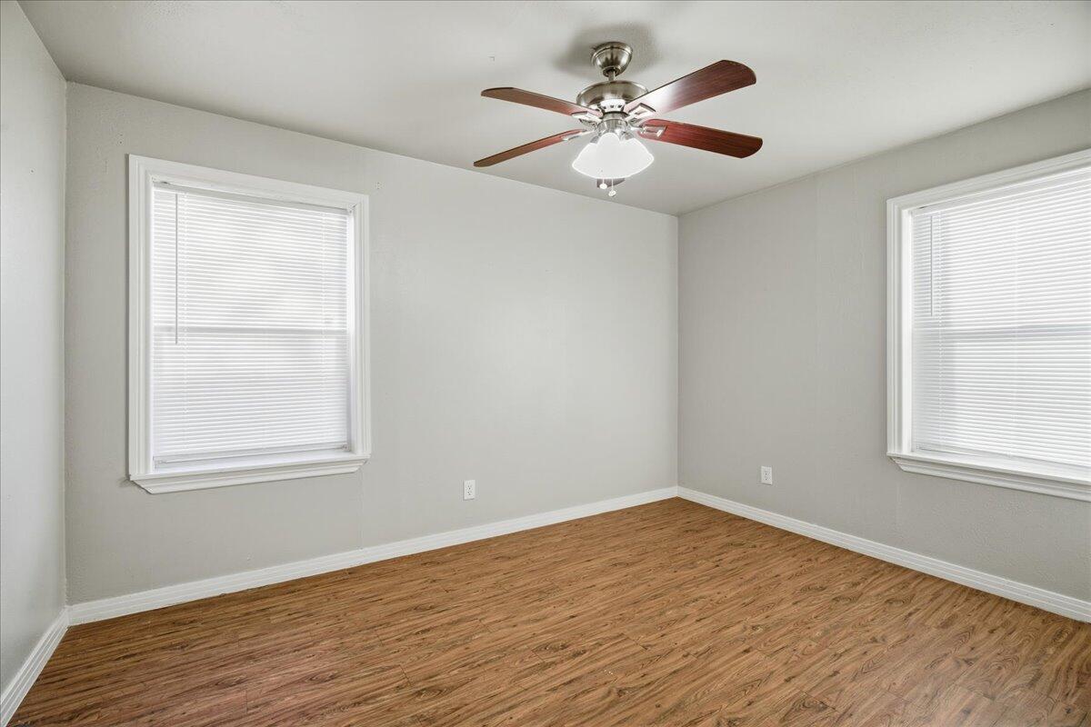 4115 31st Street Lubbock, TX 79410 - Photo 13 of 16 an empty room with wooden floor windows and fan