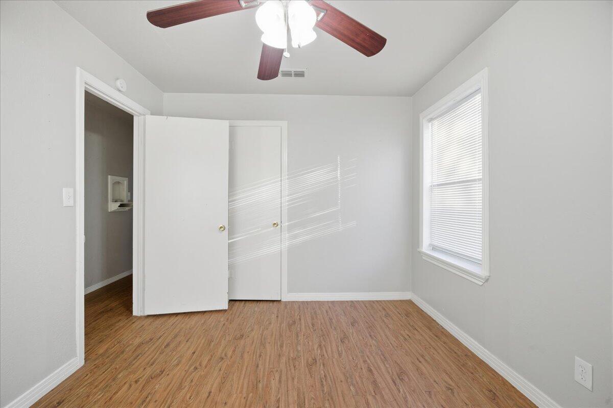 4115 31st Street Lubbock, TX 79410 - Photo 14 of 16 an empty room with wooden floor chandelier fan and windows