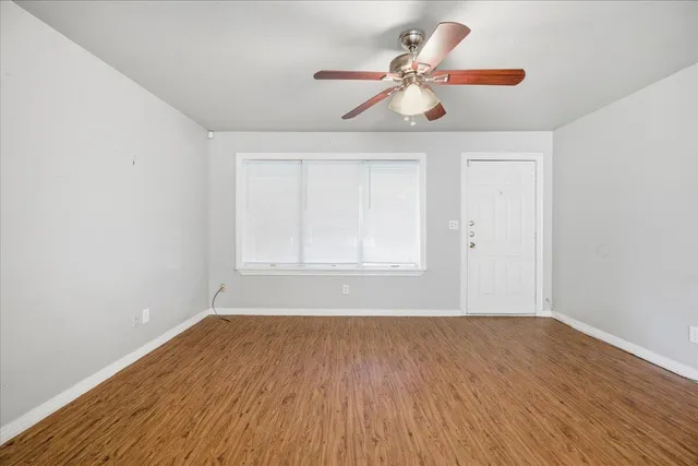 a view of room with window ceiling fan and wooden floor
