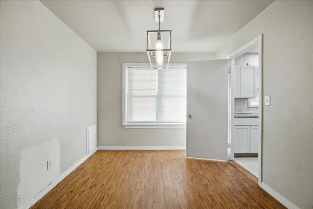 an empty room with wooden floor cabinet and windows