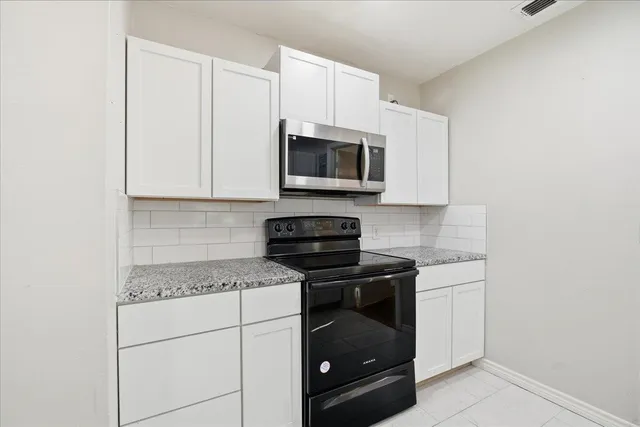 a kitchen with stainless steel appliances granite countertop white cabinets a stove a microwave and a refrigerator