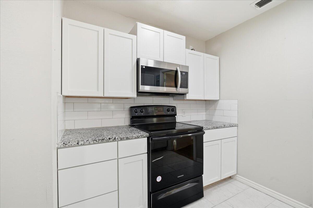 4115 31st Street Lubbock, TX 79410 - Photo 7 of 16 a kitchen with stainless steel appliances granite countertop white cabinets a stove a microwave and a refrigerator