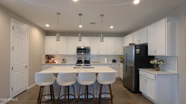 a kitchen with stainless steel appliances granite countertop a sink a stove a refrigerator with a dining table and chairs