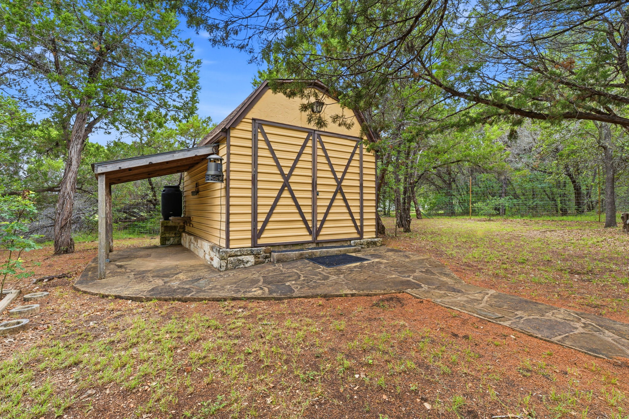 8121 Bluff Trail Austin, TX 78737 - Photo 40 of 40 This quaint outbuilding offers rustic charm amidst a lush, wooded landscape.