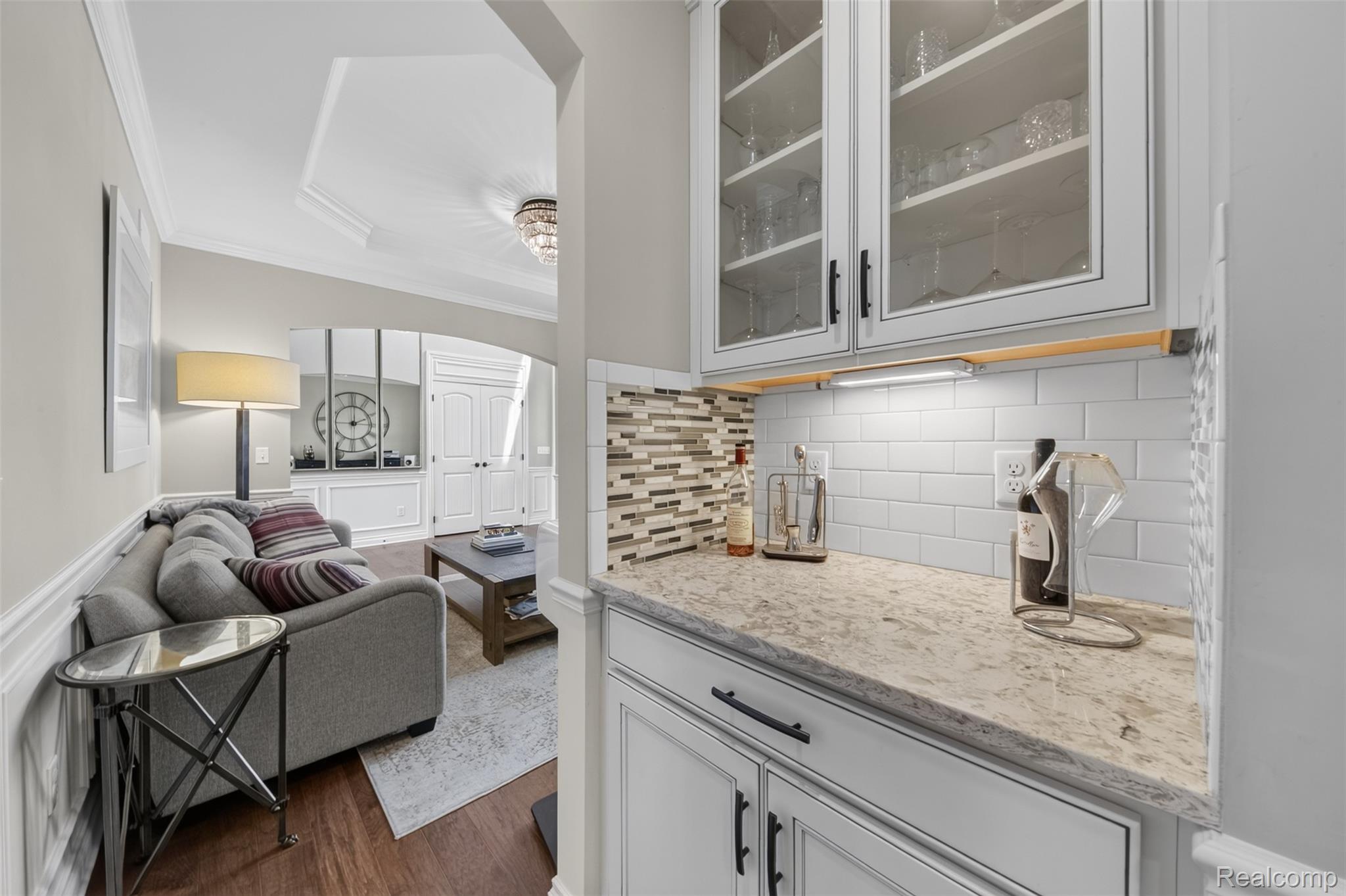 2531 Walnut View Drive Howell, MI 48855 - Photo 17 of 34 Built-in wet bar featuring upper glass-front cabinetry, a subway tile backsplash, and a stone countertop