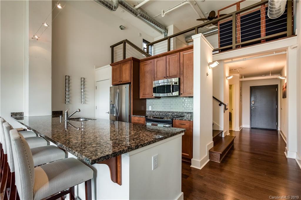 715 North Graham Street, Unit 210 Charlotte, NC 28202 - Photo 2 of 17 a kitchen with kitchen island granite countertop a table chairs refrigerator and sink