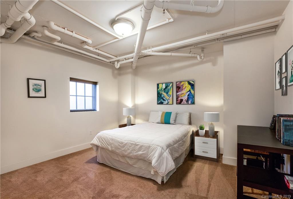 715 North Graham Street, Unit 210 Charlotte, NC 28202 - Photo 4 of 17 a bedroom with a bed and a view of kitchen
