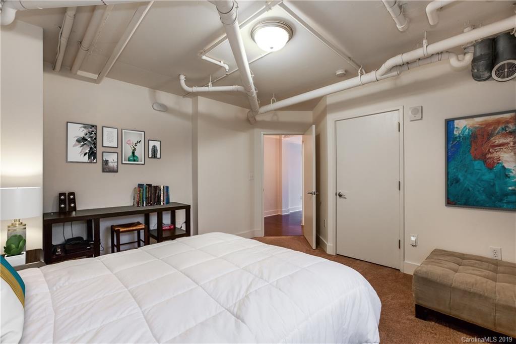 715 North Graham Street, Unit 210 Charlotte, NC 28202 - Photo 5 of 17 a bedroom with a bed and a chandelier