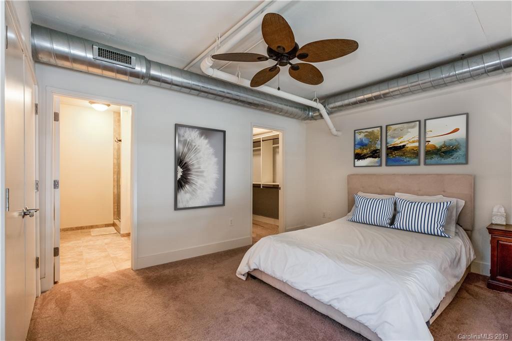 715 North Graham Street, Unit 210 Charlotte, NC 28202 - Photo 8 of 17 a bedroom with a large bed and ceiling fan