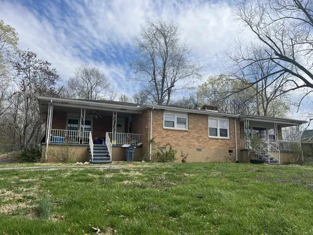 a backyard of a house with barbeque oven and large tree
