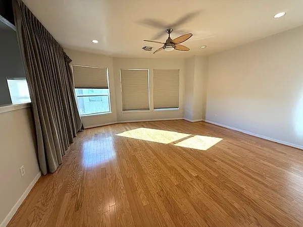 an empty room with wooden floor and windows