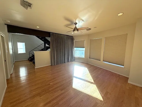 a view of an empty room with window and wooden floor