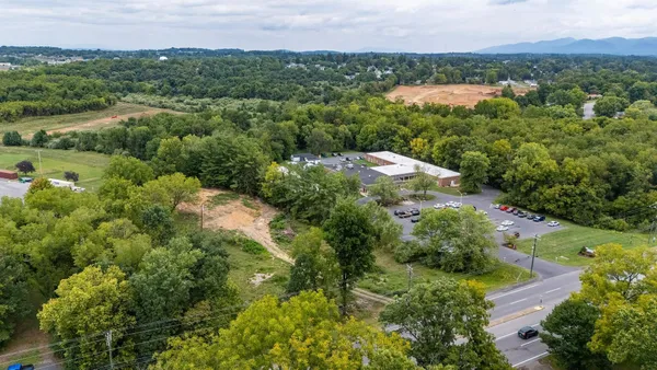 an aerial view of green landscape with trees houses and mountain view